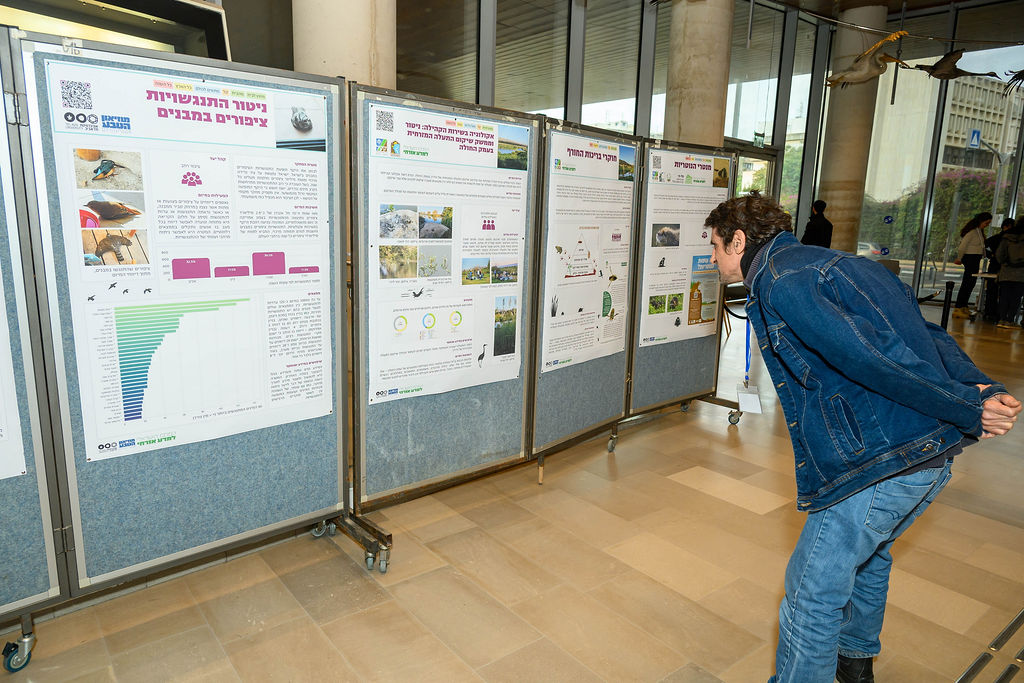 משתתף בכנס מביט בפוסטרים של מיזמים